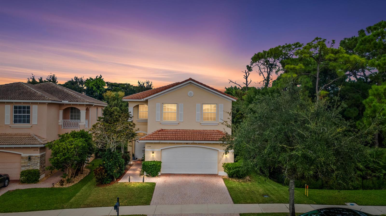 A two-story suburban house with a tiled roof and a paved driveway at sunset — 1104 NW Leonardo Circle, FL 34986, FL