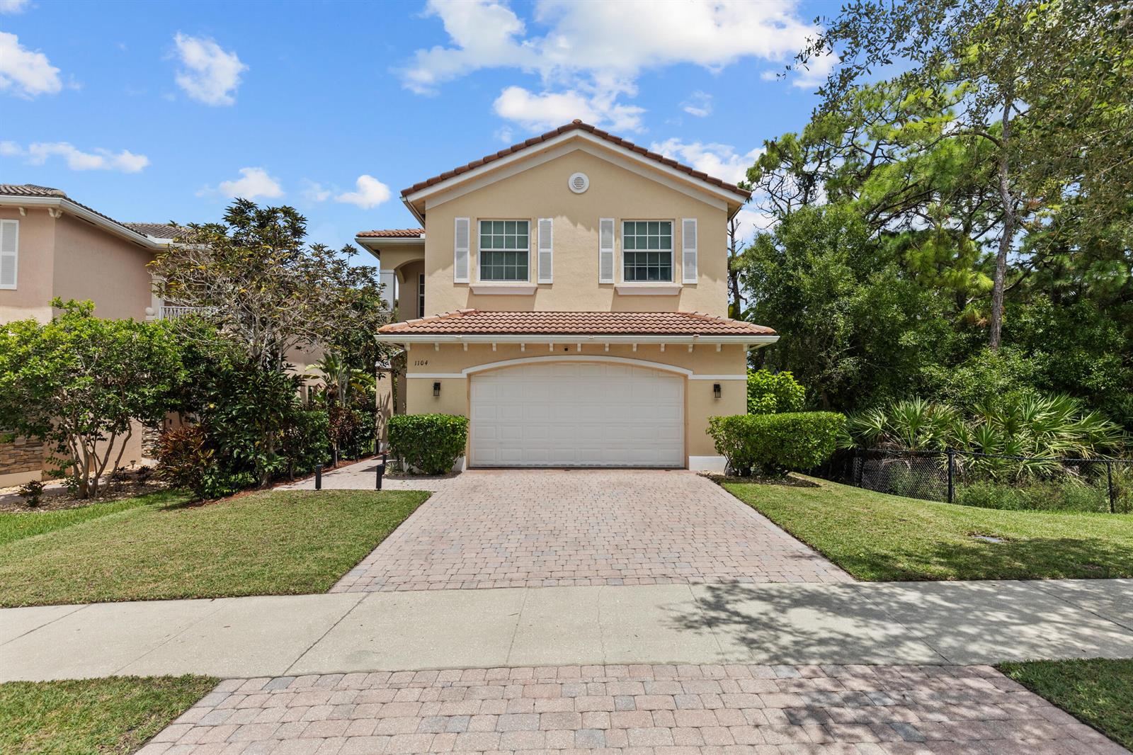 A two-story house with a beige stucco exterior, a tiled roof, and a paved driveway — 1104 NW Leonardo Circle, FL 34986, FL