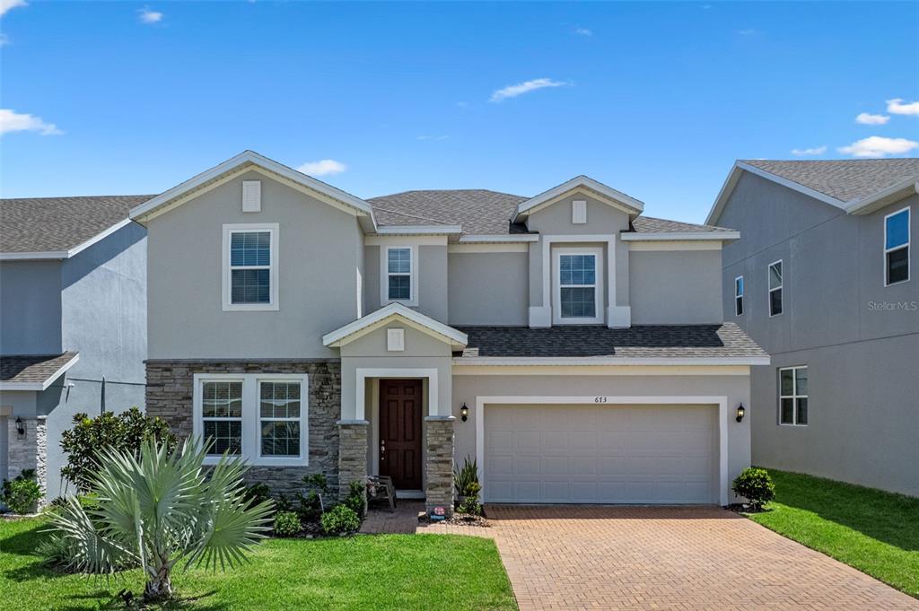 A two-story suburban house with a stone-accented facade, a two-car garage, and a brick driveway — 673 BLACKSTONE STREET, MINNEOLA, FL