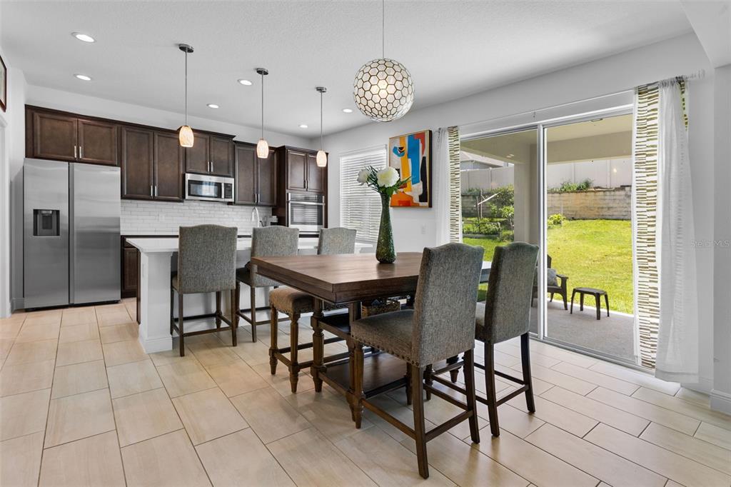 A kitchen with dark wood cabinets, a center island, and a dining area with patio access — 673 BLACKSTONE STREET, MINNEOLA, FL