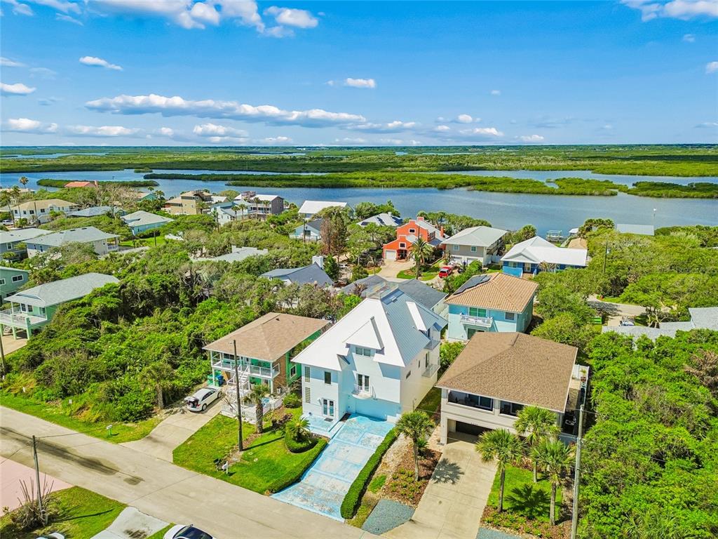 An aerial view shows a white house with a metal roof surrounded by coastal vegetation — 6340 ENGRAM ROAD, NEW SMYRNA BEACH, FL