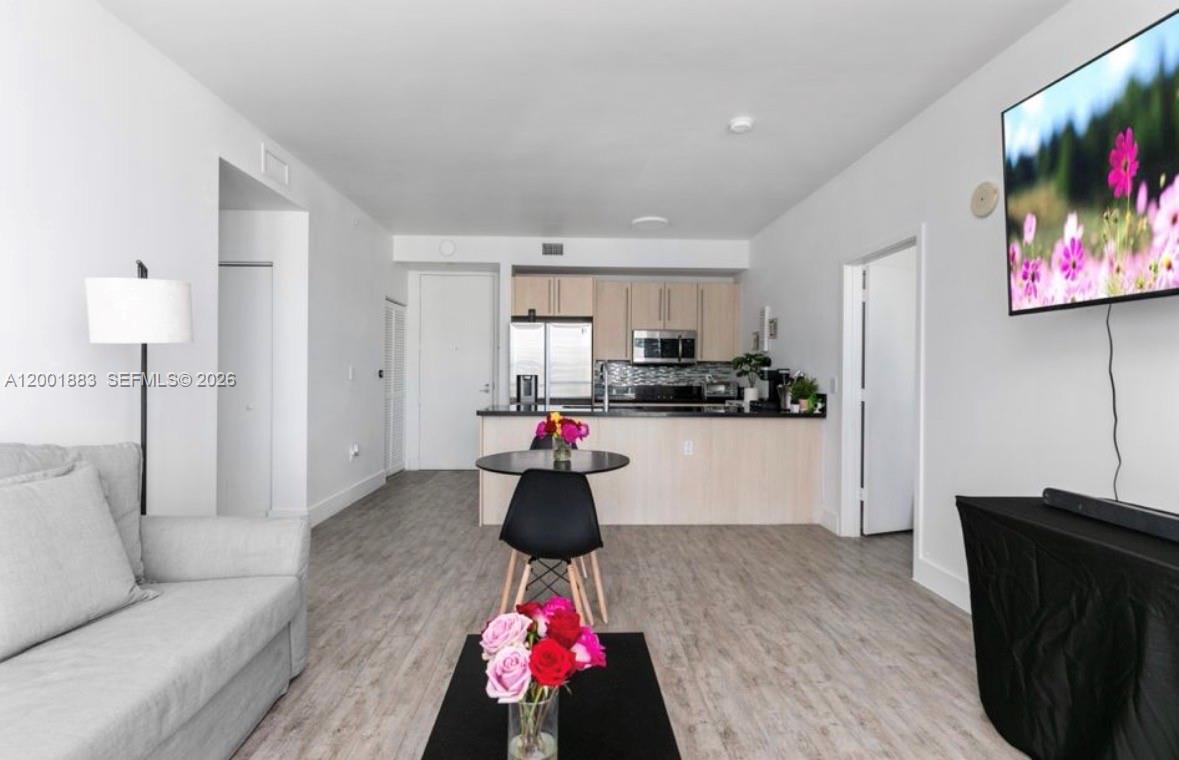A living room with light wood flooring flows into an open kitchen with light cabinetry — 1111 SW 1st Ave, Miami FL 33130, MIAMI, FL