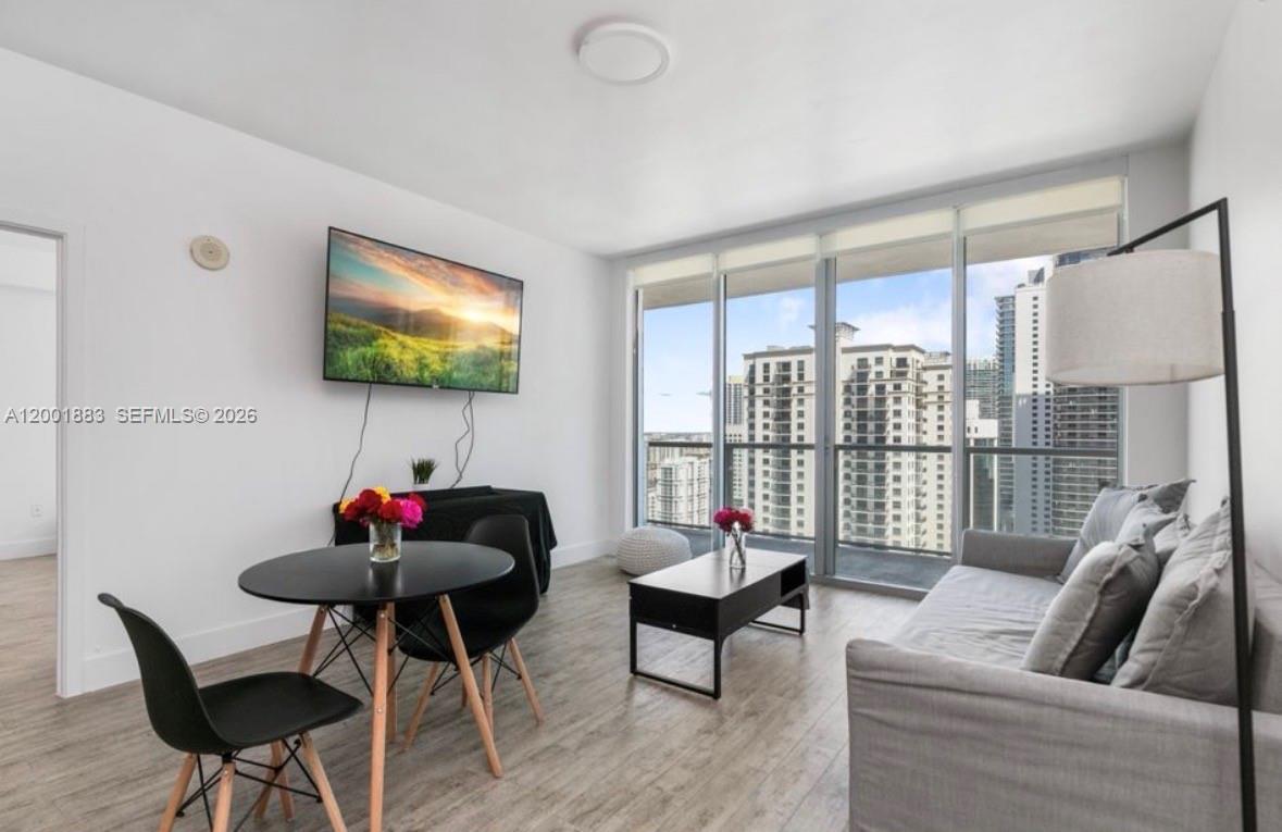 A modern living room features a dining area, a sofa, and floor-to-ceiling windows — 1111 SW 1st Ave, Miami FL 33130, MIAMI, FL