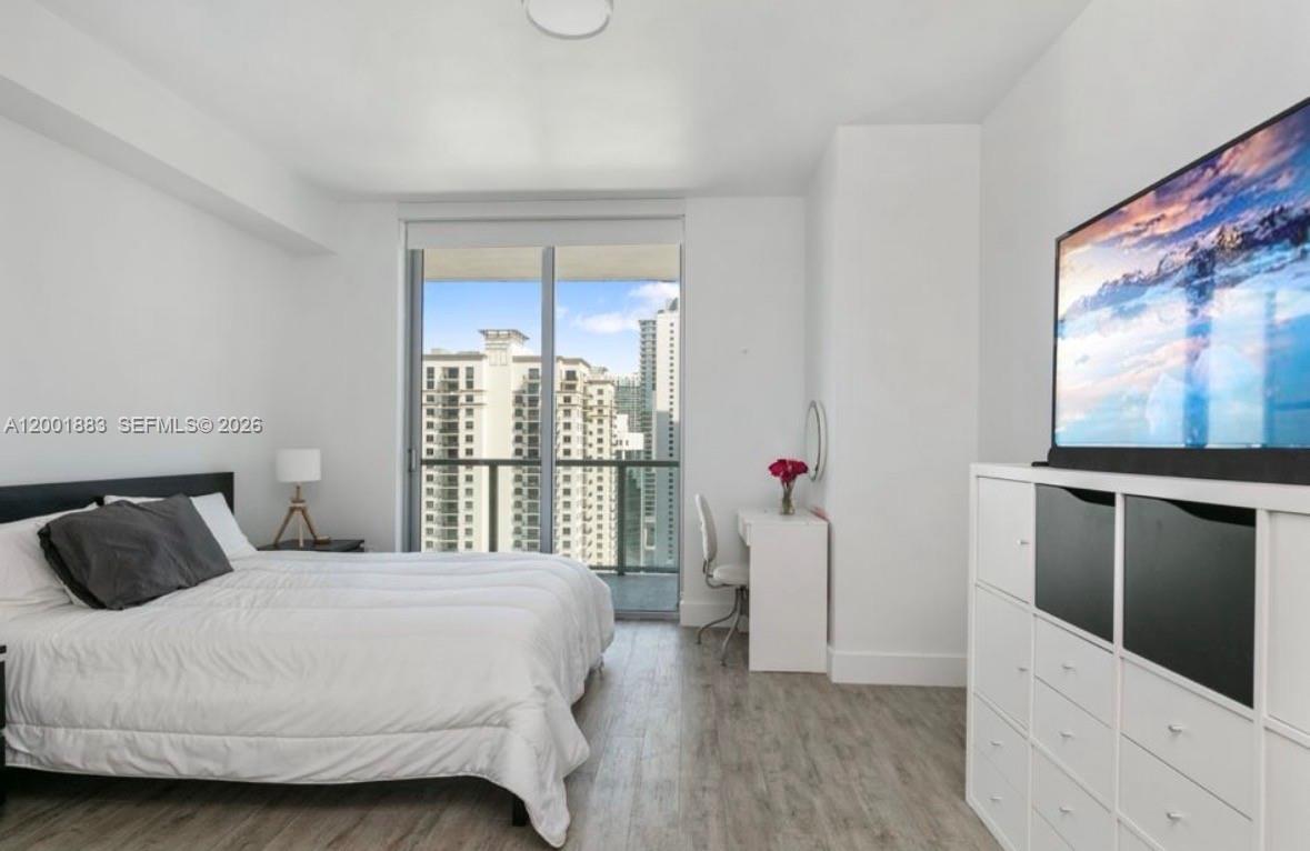 A bedroom with a bed, a desk, a storage unit with a television, and a balcony — 1111 SW 1st Ave, Miami FL 33130, MIAMI, FL