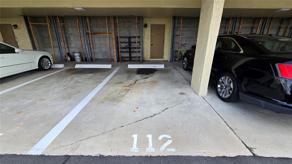A covered parking space marked 112 is situated between two parked cars — 105 ISLAND WAY UNIT 112, CLEARWATER BEACH, FL