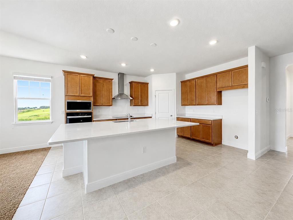 A kitchen with white countertops, wooden cabinets, a center island, and tiled flooring — 2244 AXEL STREET, MINNEOLA, FL
