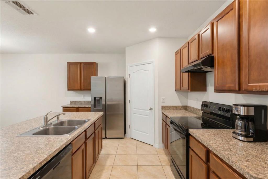 A kitchen features wood cabinets, laminate countertops, stainless steel appliances, and a central island — 943 SUMMER GLEN DRIVE, WINTER HAVEN, FL