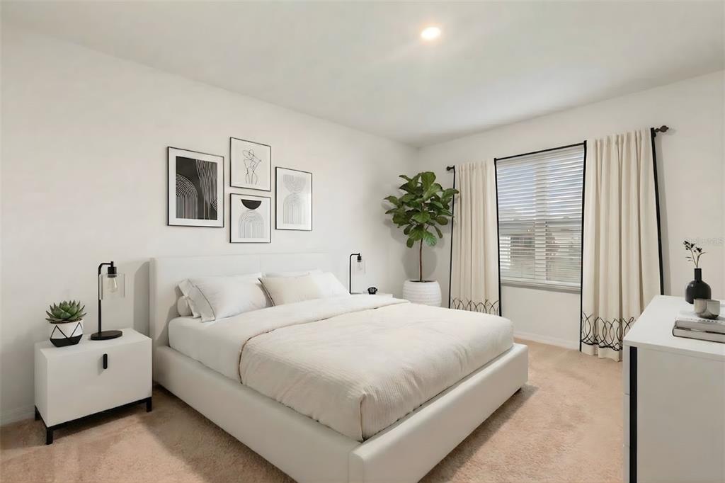 A modern bedroom features a white platform bed, neutral bedding, wall art, and a potted plant — 943 SUMMER GLEN DRIVE, WINTER HAVEN, FL