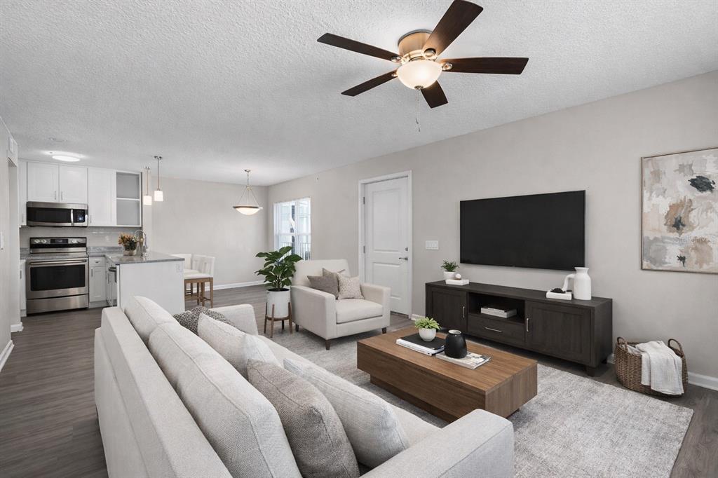 A living room with a sofa, armchair, coffee table, and television opens to a kitchen — 1974 S GOLDENROD ROAD ROAD UNIT 106, ORLANDO, FL