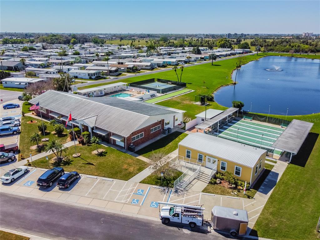 An aerial view shows a community center with a pool, tennis courts, and a lake — 2900 8TH AVENUE W UNIT 18, PALMETTO, FL