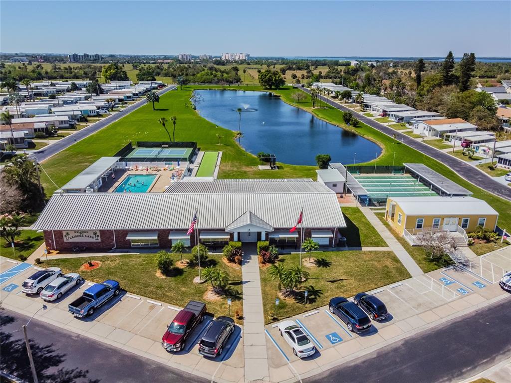 An aerial view shows a community center with a pool, tennis courts, and a lake — 2900 8TH AVENUE W UNIT 18, PALMETTO, FL
