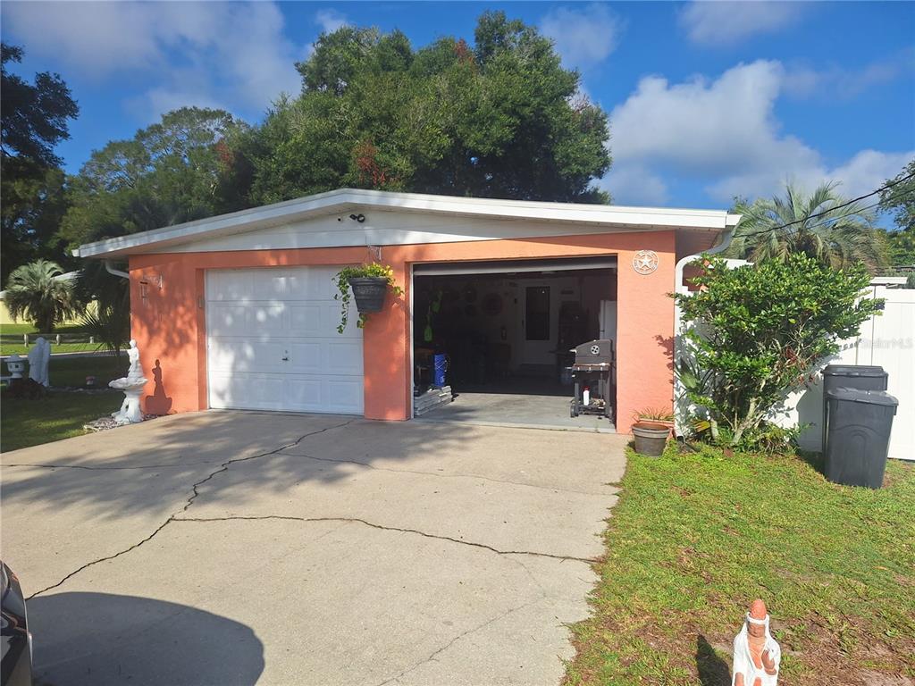A peach-colored house features a two-car garage with one open bay and a concrete driveway — 3755 SE 139TH STREET, SUMMERFIELD, FL