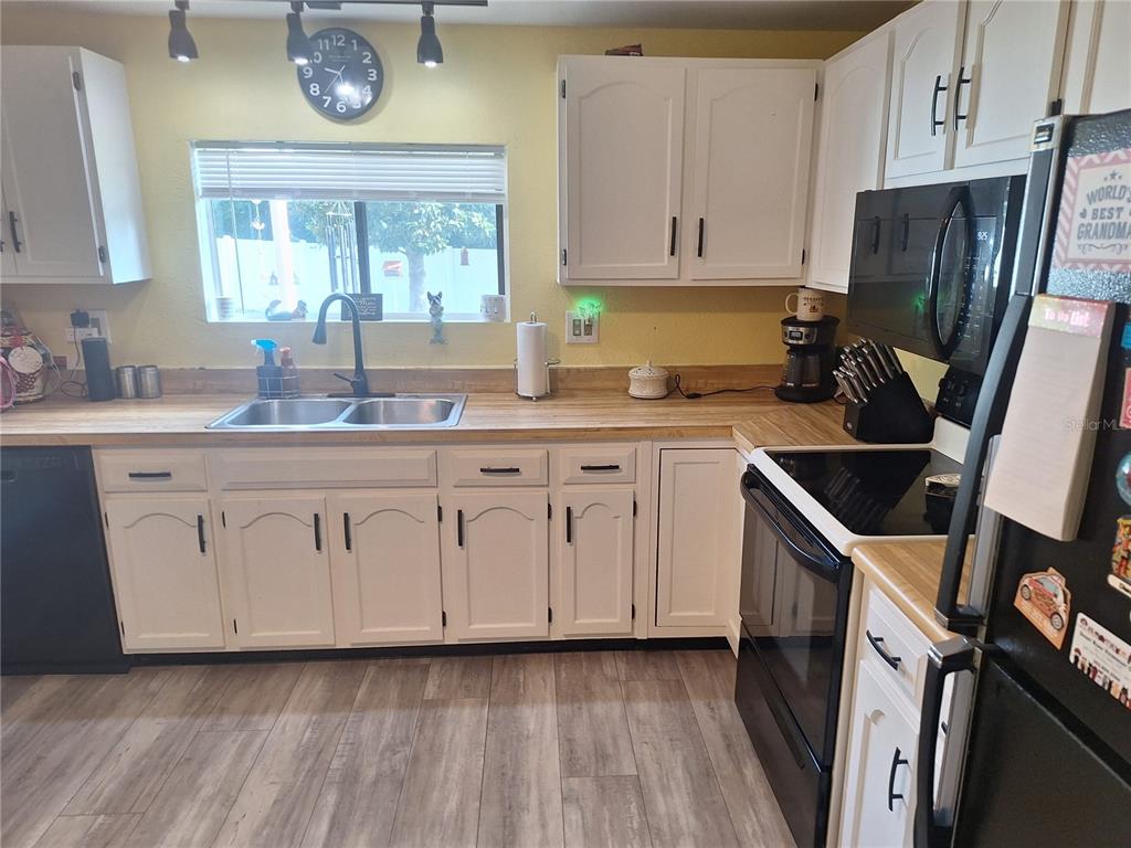 A kitchen features white cabinets, wood countertops, a double sink, and black appliances — 3755 SE 139TH STREET, SUMMERFIELD, FL