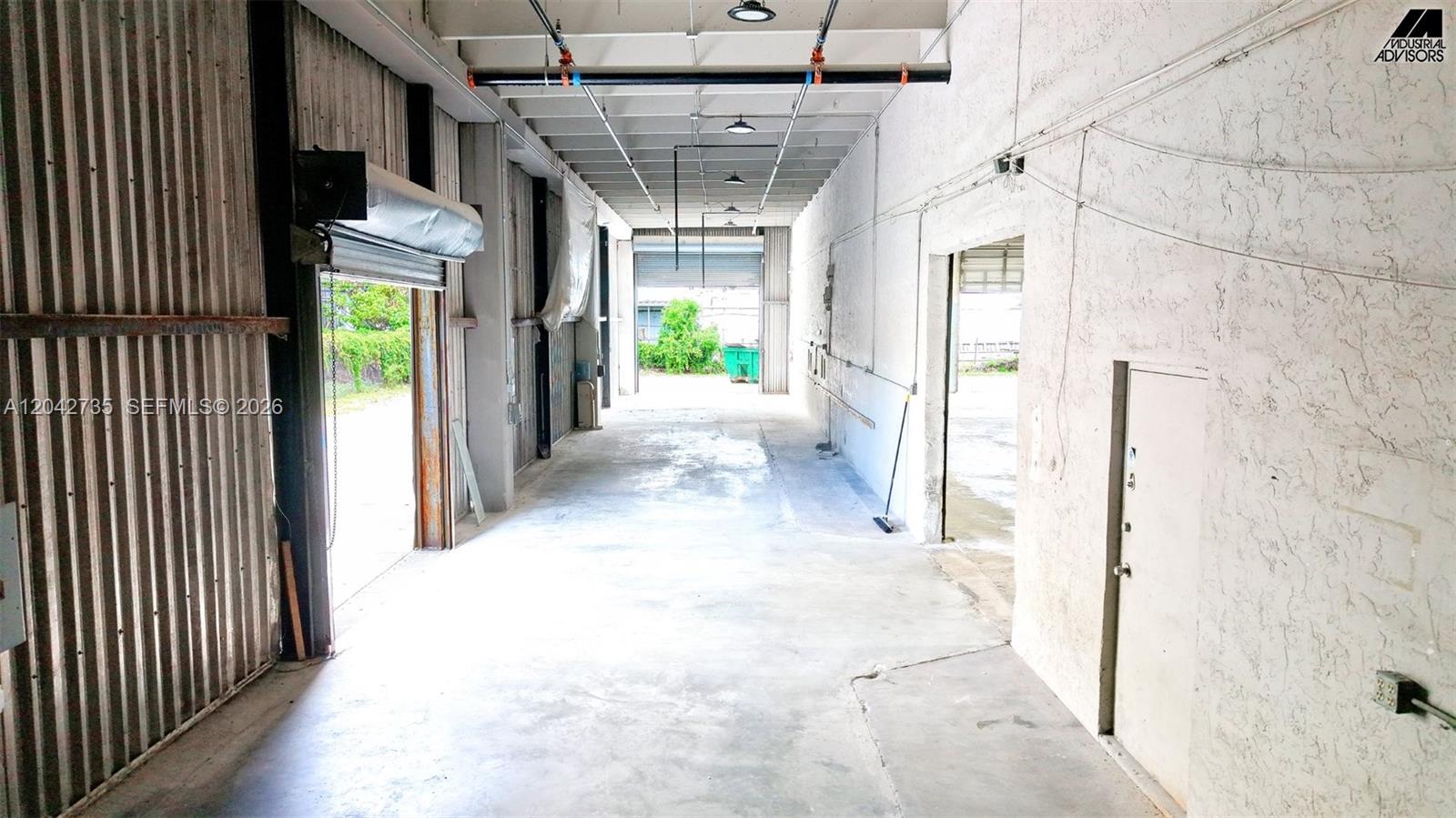 An industrial warehouse interior features concrete floors, metal walls, and a roll-up loading door — 16350 NW 48th Ave, Miami Lakes FL 33014, MIAMI LAKES, FL