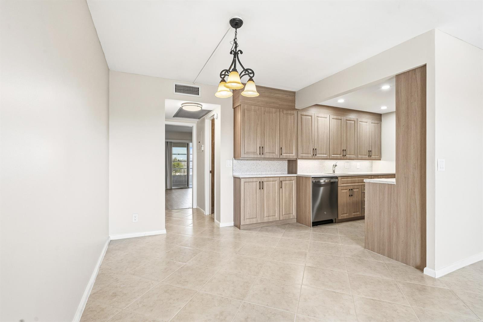 A kitchen features light wood cabinets, a stainless steel dishwasher, and beige tile flooring — 4067 Yarmouth D, Boca Raton FL 33434, BOCA RATON, FL