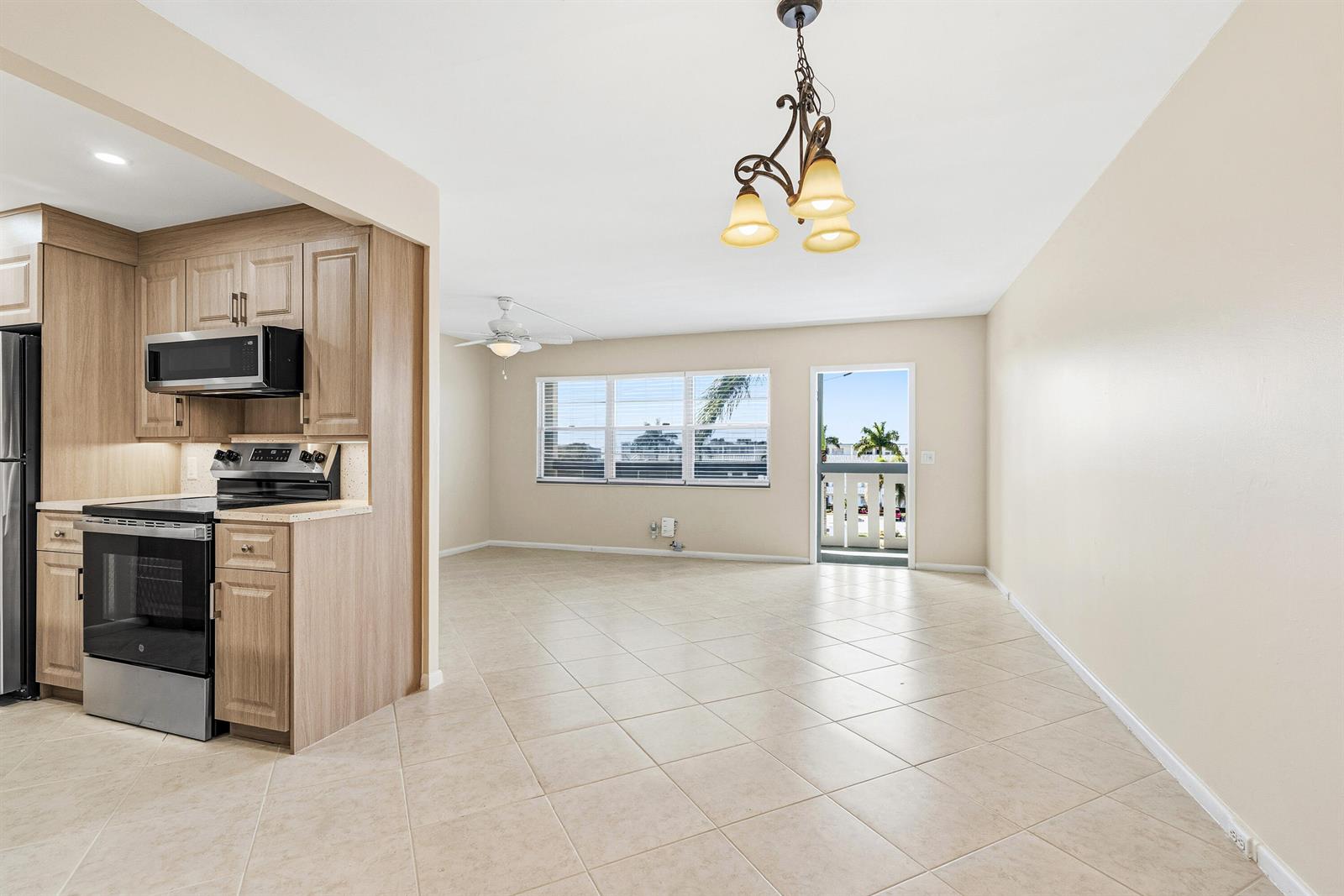 A kitchen with light wood cabinets and stainless steel appliances opens into a tiled living area — 4067 Yarmouth D, Boca Raton FL 33434, BOCA RATON, FL