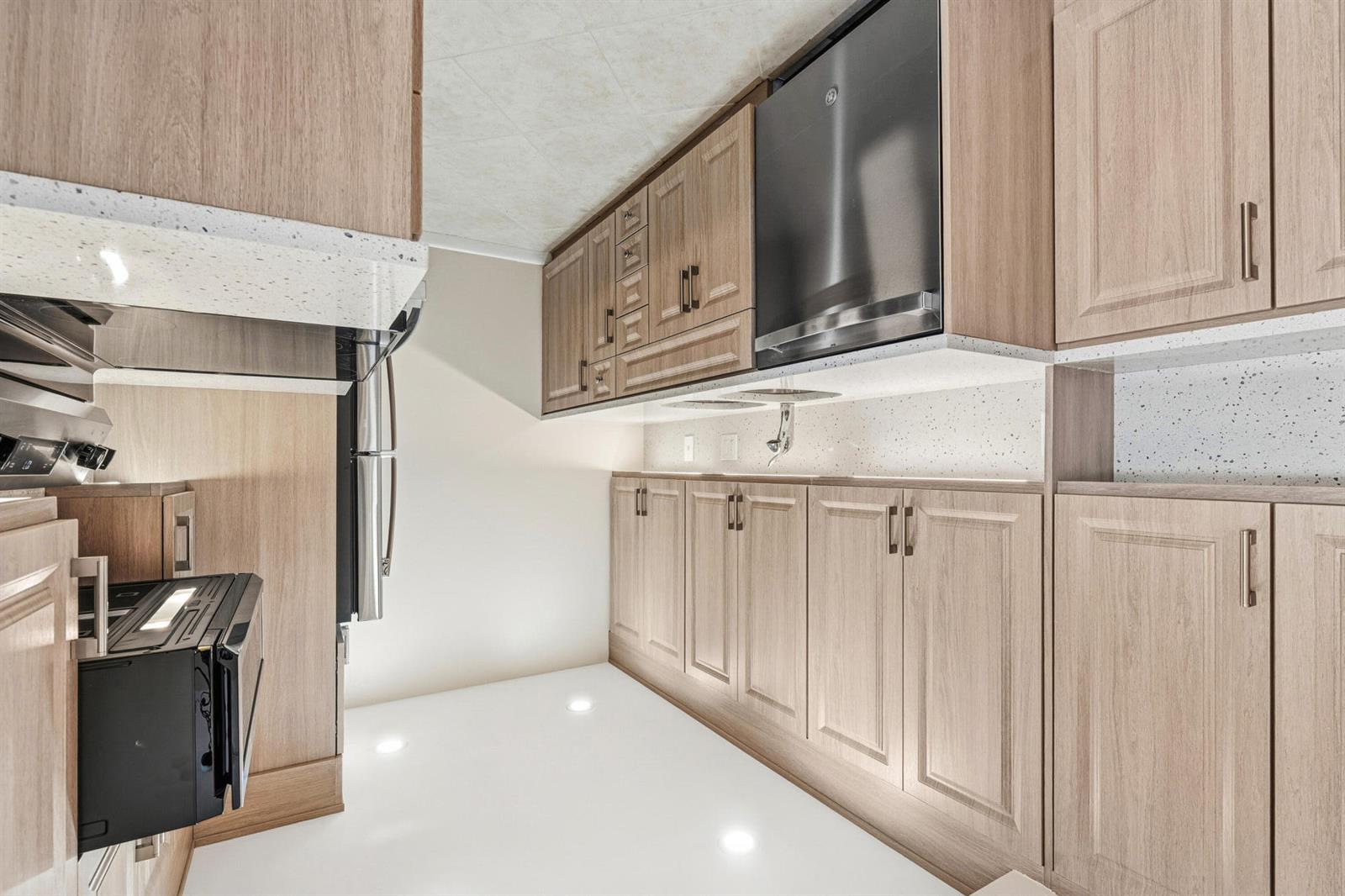 A kitchen featuring light wood cabinetry, white speckled countertops, and stainless steel appliances — 4067 Yarmouth D, Boca Raton FL 33434, BOCA RATON, FL