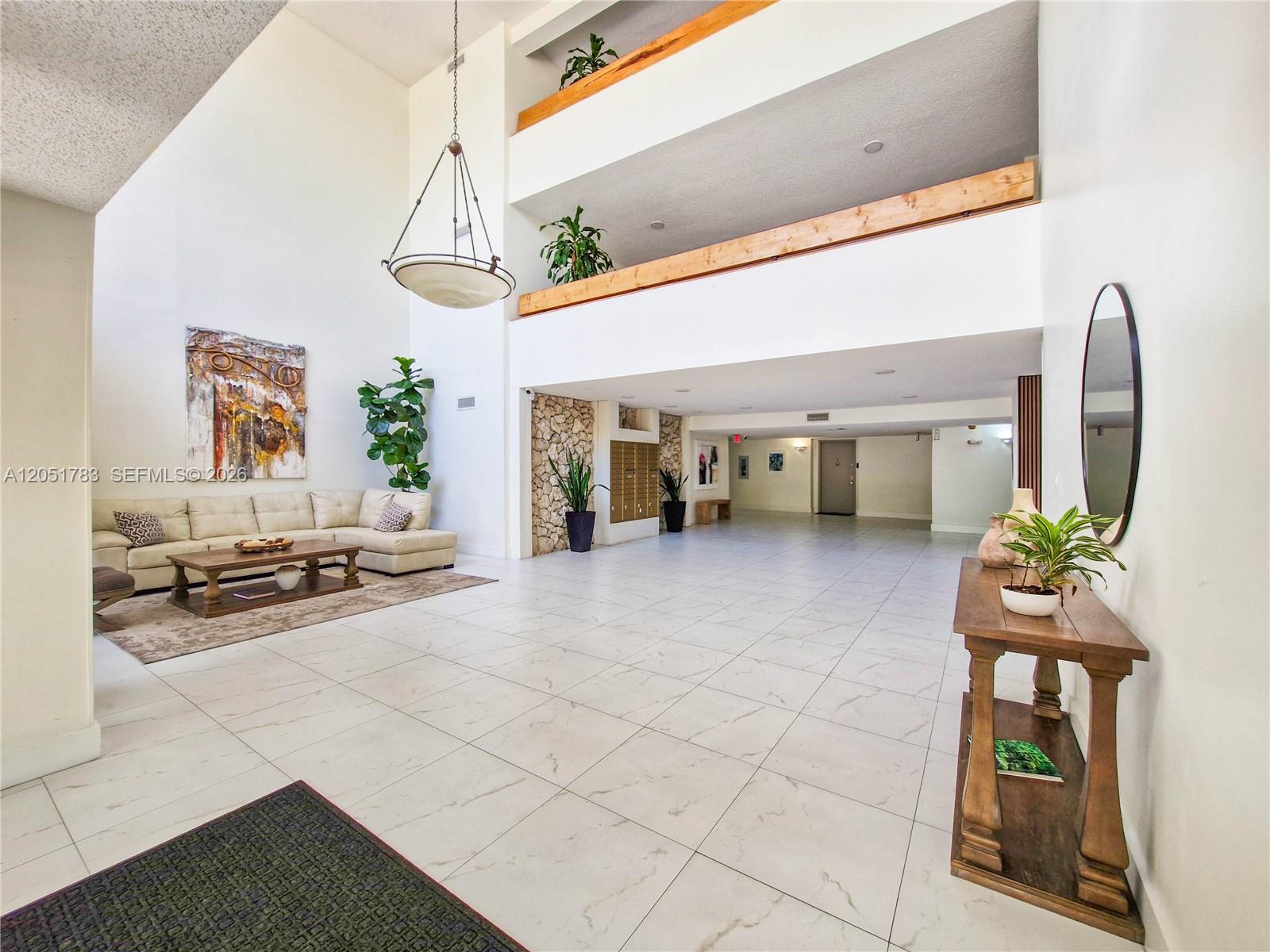 A spacious lobby features white tile floors, a high ceiling, and a seating area — 16200 Golf Club Rd # 109, Weston FL 33326, WESTON, FL