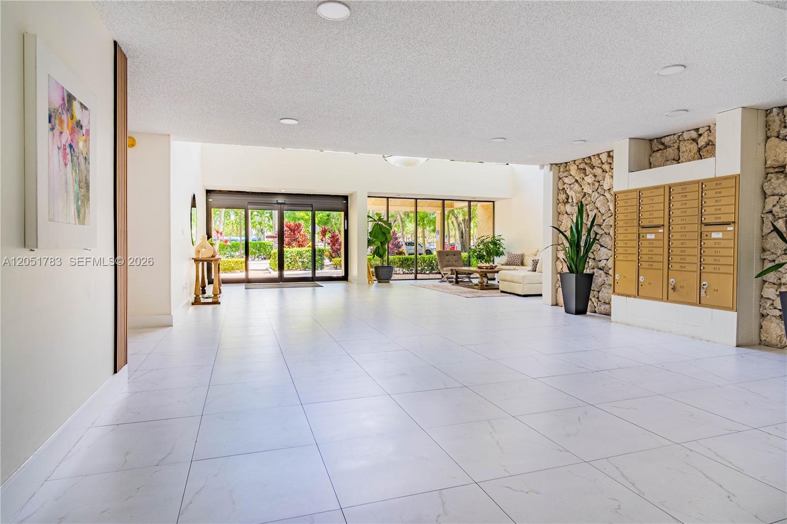 A bright lobby features white tile floors, a stone accent wall, and a mailroom area — 16200 Golf Club Rd # 109, Weston FL 33326, WESTON, FL