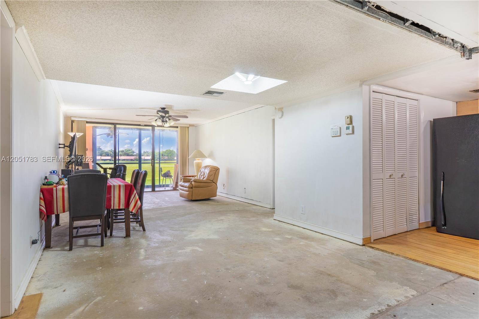 An open-concept room features a dining area, a living space, and unfinished concrete flooring — 16200 Golf Club Rd # 109, Weston FL 33326, WESTON, FL
