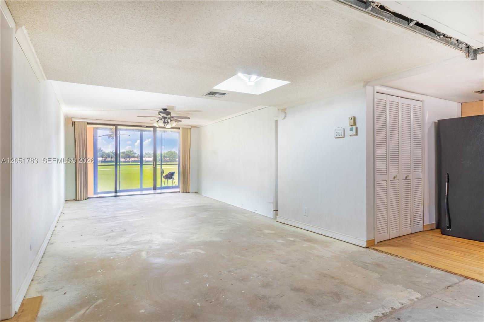 An unfinished room features a concrete floor, a ceiling fan, a skylight, and sliding glass doors — 16200 Golf Club Rd # 109, Weston FL 33326, WESTON, FL