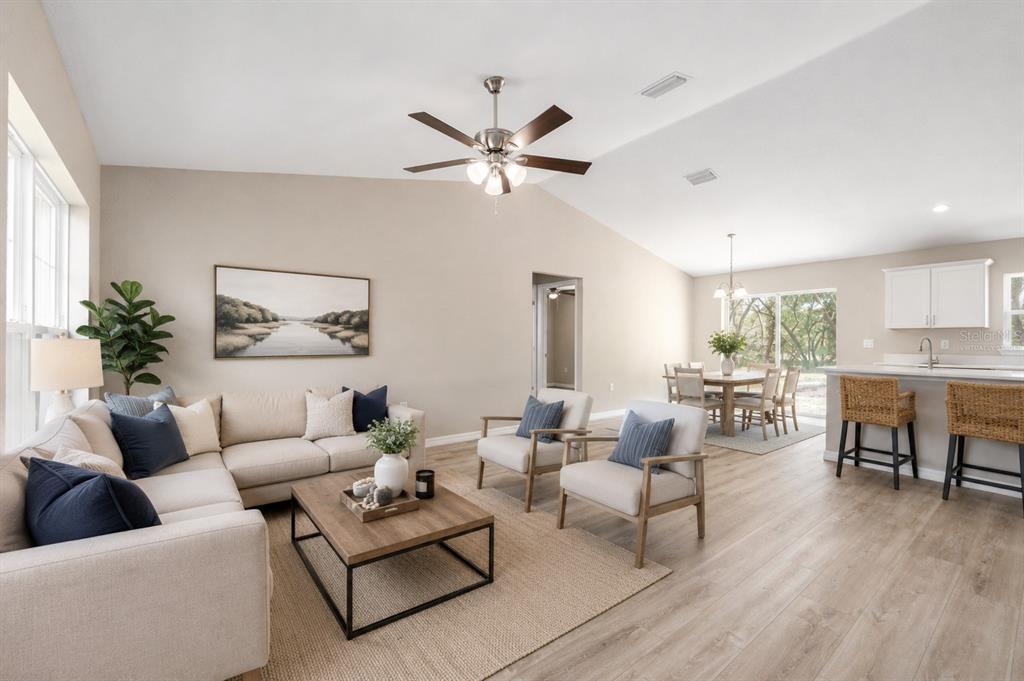 A living room with a sectional sofa, two armchairs, and an open-concept kitchen and dining area — 13 PECAN PASS TRAIL, OCALA, FL