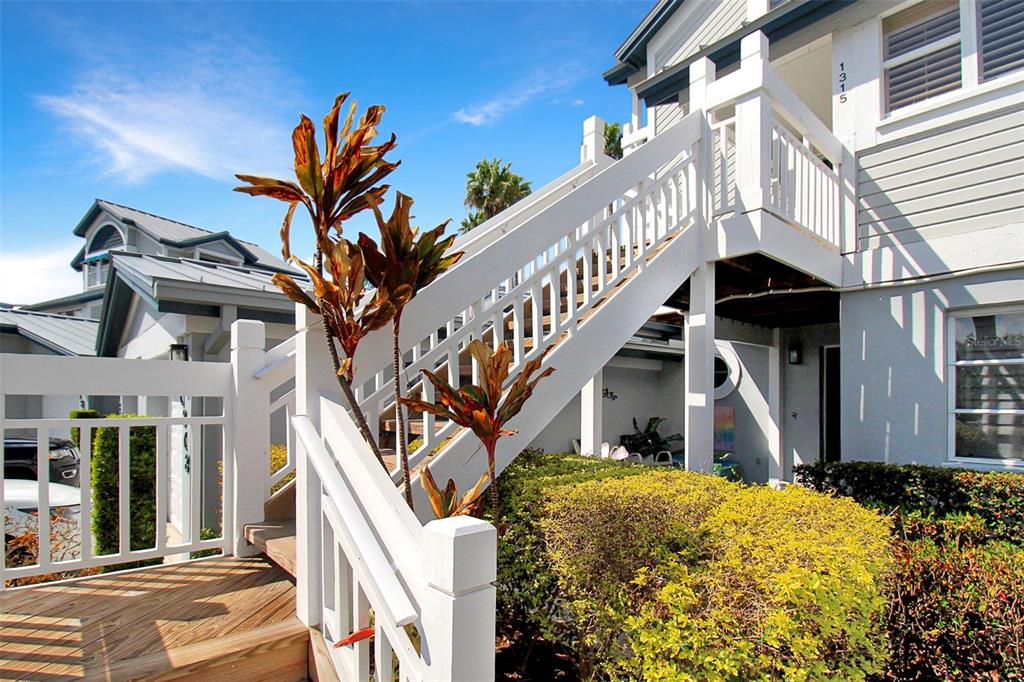 A white exterior staircase leads to the upper level of a house with landscaping — 1315 SIESTA BAYSIDE DRIVE UNIT 1315B, SARASOTA, FL
