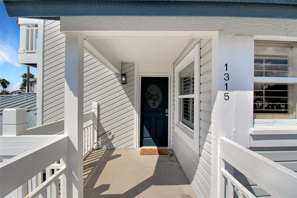 A covered porch leads to a dark blue front door with a house number displayed nearby — 1315 SIESTA BAYSIDE DRIVE UNIT 1315B, SARASOTA, FL