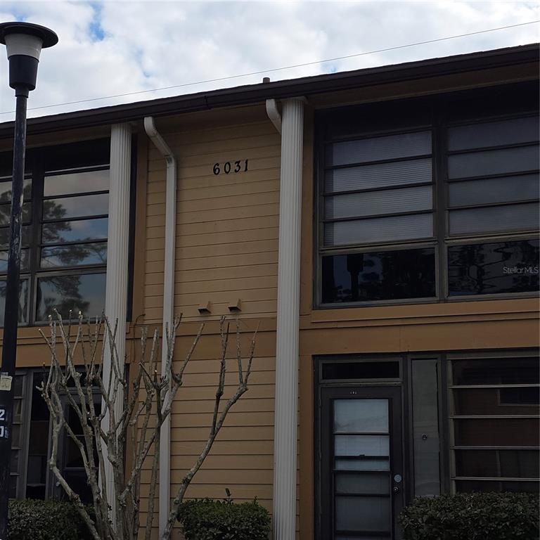 A two-story tan building exterior features vertical columns, horizontal siding, and multiple windows — 6031 SCOTCHWOOD GLEN UNIT 204, ORLANDO, FL