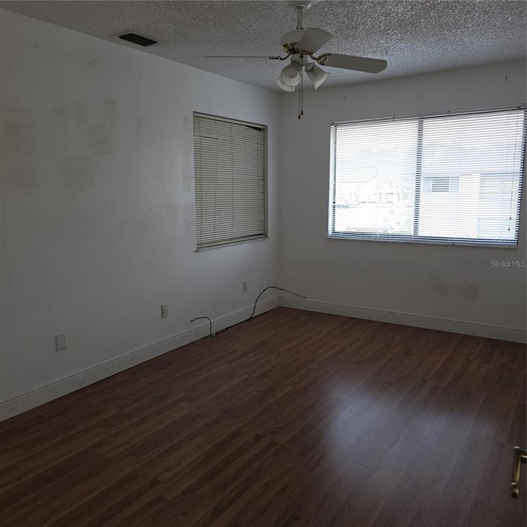 An empty bedroom features wood-look flooring, white walls, two windows with blinds, and a ceiling fan — 6031 SCOTCHWOOD GLEN UNIT 204, ORLANDO, FL