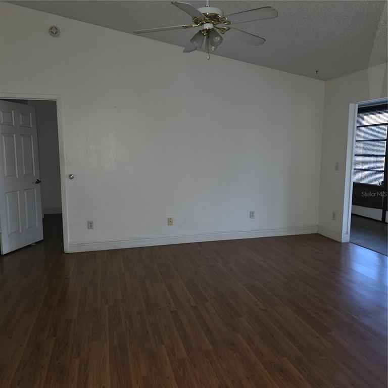An empty room with wood-look flooring, white walls, a ceiling fan, and two doorways — 6031 SCOTCHWOOD GLEN UNIT 204, ORLANDO, FL