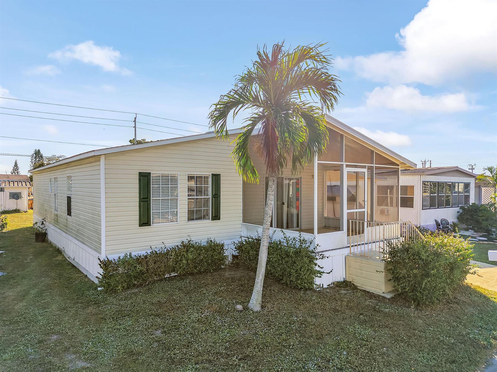 A light-yellow mobile home features a screened-in front porch and a single palm tree — 4920 NW 2nd Terrace, Pompano Beach FL 33064, POMPANO BEACH, FL