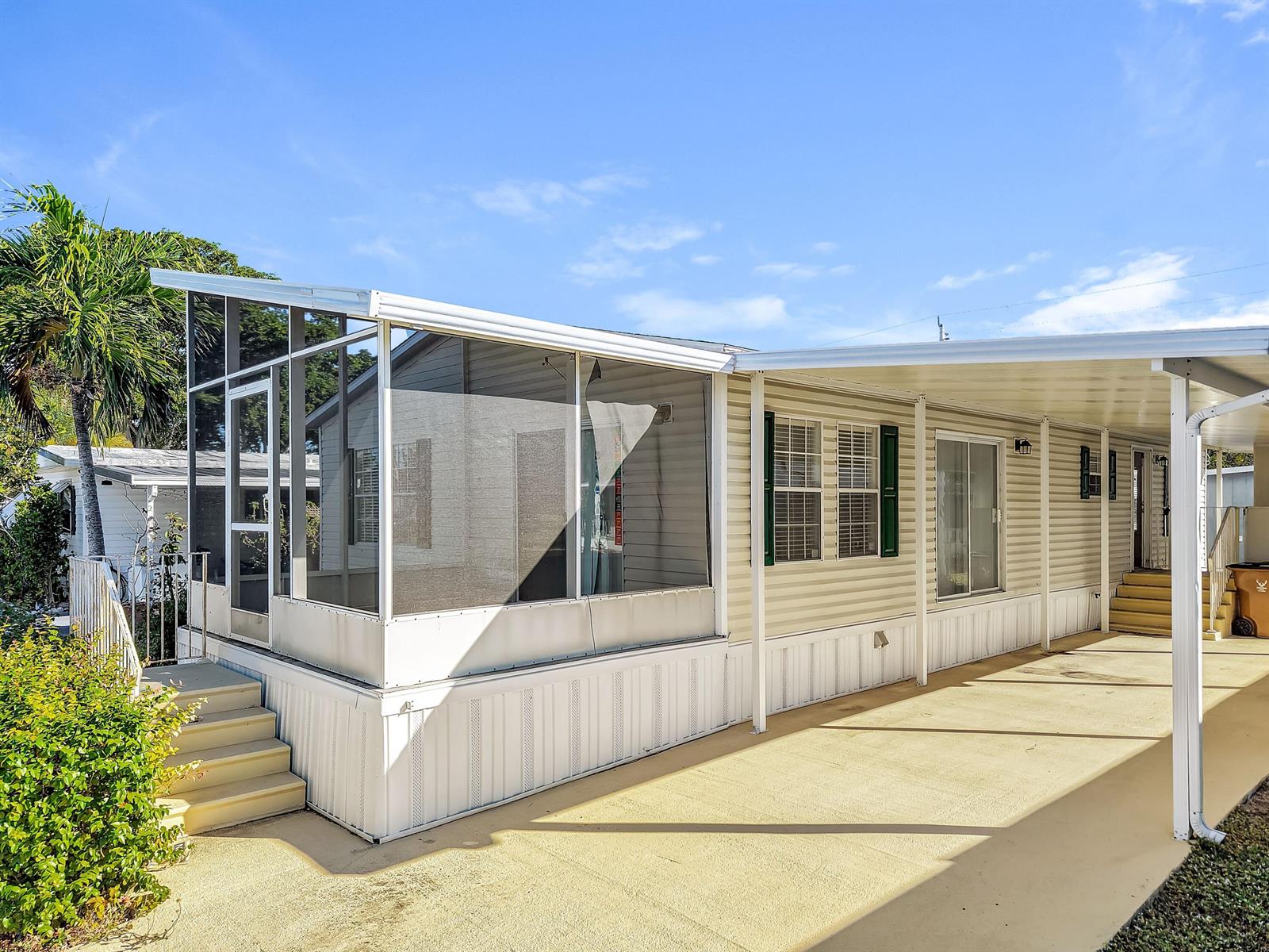 A mobile home exterior features a screened-in porch, a covered carport, and beige siding — 4920 NW 2nd Terrace, Pompano Beach FL 33064, POMPANO BEACH, FL