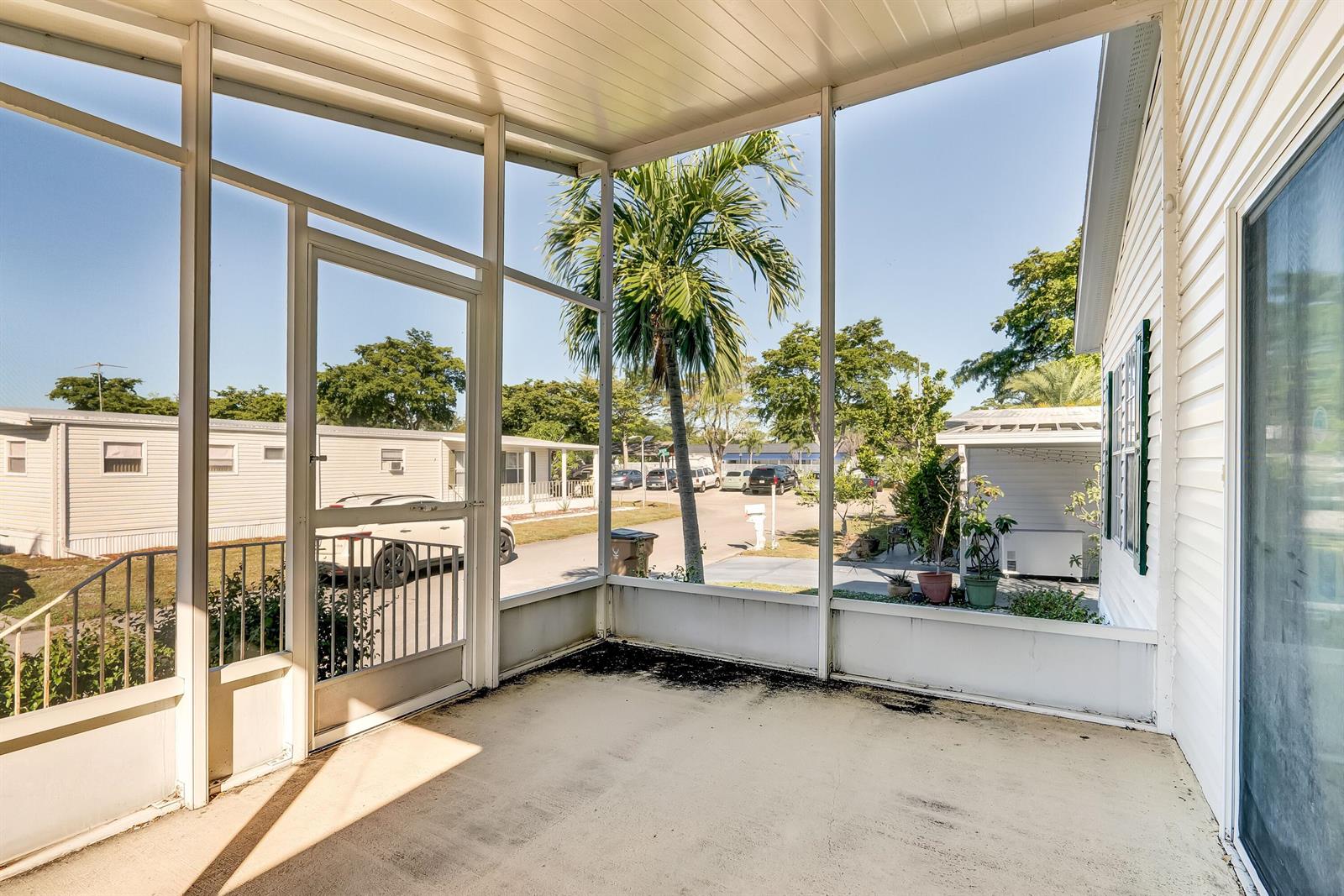 A screened-in porch with a concrete floor overlooks a residential street with parked cars — 4920 NW 2nd Terrace, Pompano Beach FL 33064, POMPANO BEACH, FL