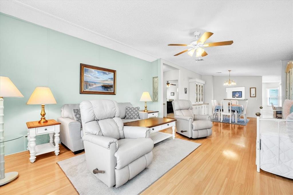 A living room features light blue walls, light wood flooring, a ceiling fan, and recliners — 15550 BURNT STORE ROAD UNIT 87, PUNTA GORDA, FL