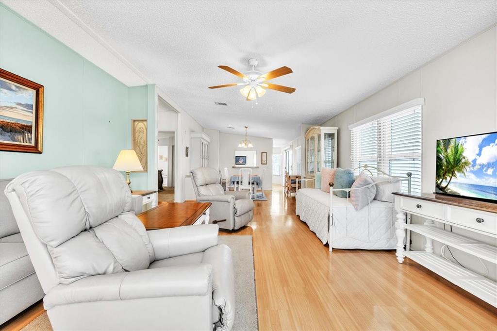 A living room features light wood flooring, a ceiling fan, and a white recliner — 15550 BURNT STORE ROAD UNIT 87, PUNTA GORDA, FL