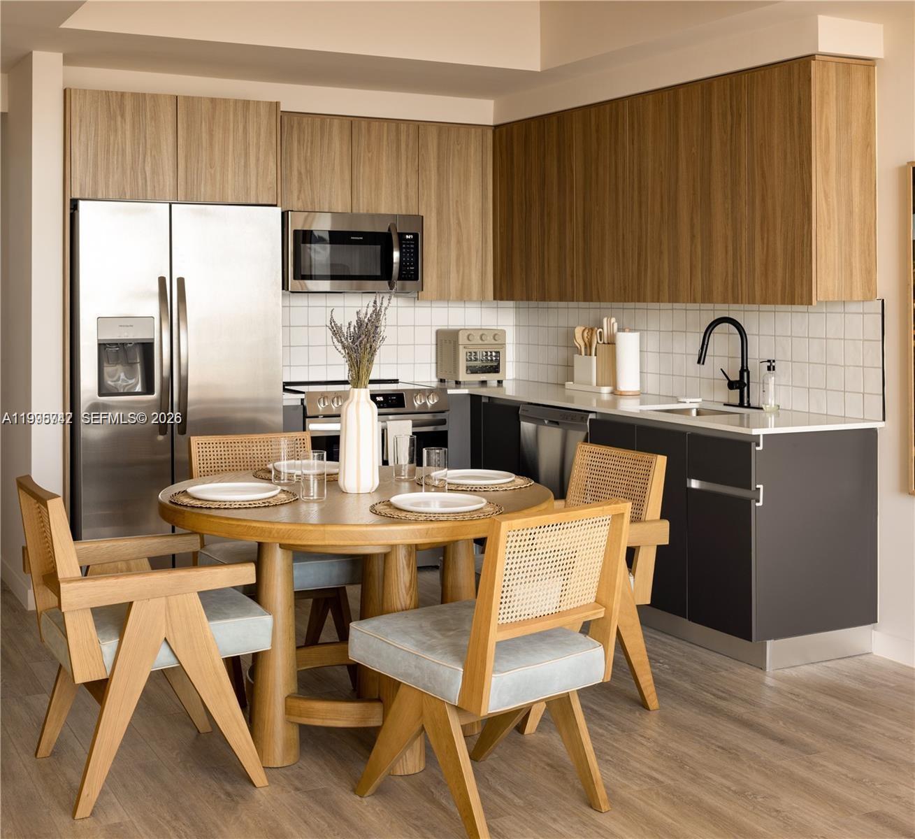 A kitchen features wood-toned upper cabinets, dark lower cabinets, stainless steel appliances, and a dining set — 275 SW 6th St # 806, Miami FL 33130, MIAMI, FL