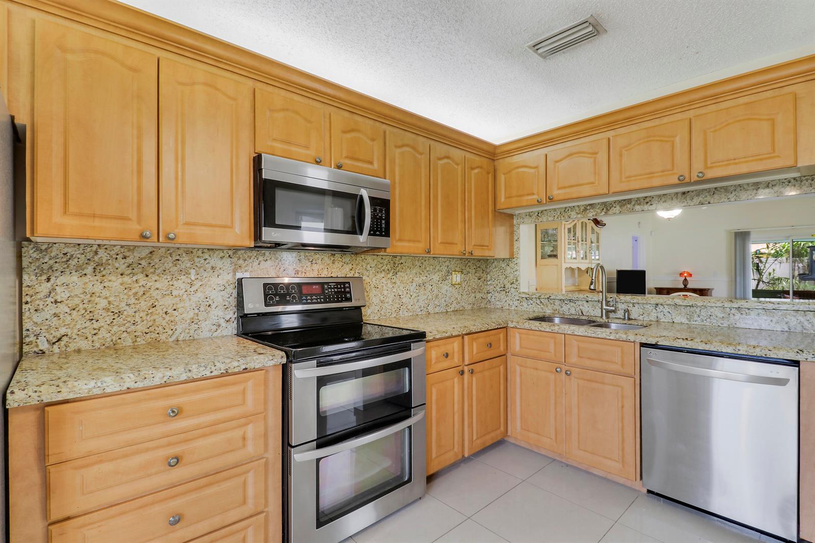 A kitchen with light wood cabinets, granite countertops, and stainless steel appliances — 5373 Gene Circle, West Palm Beach FL 33415, WEST PALM BEACH, FL