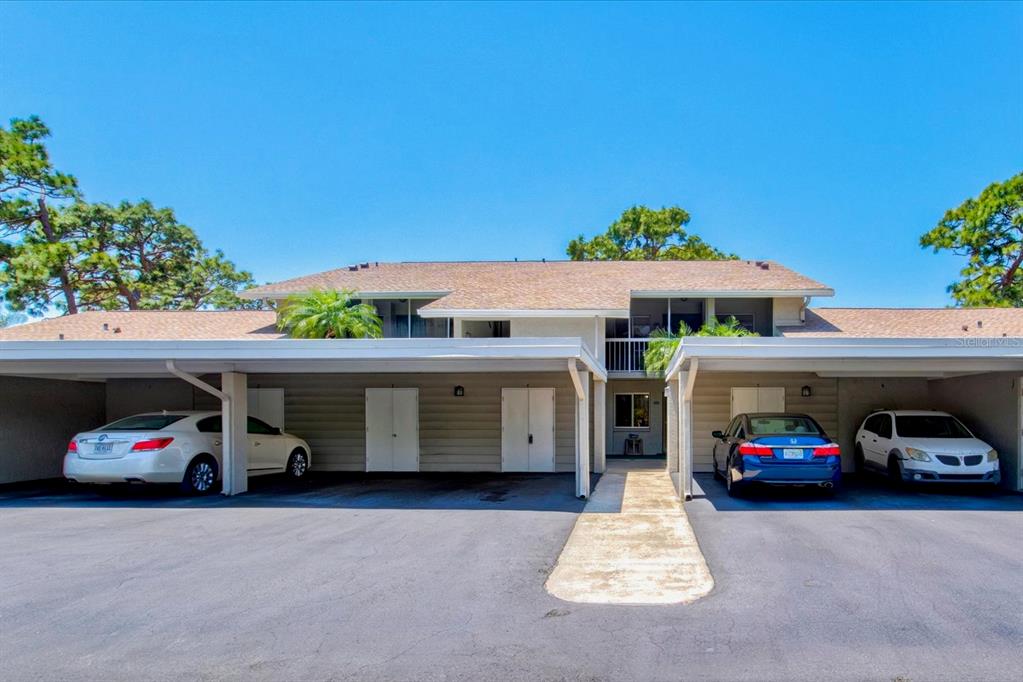 A two-story apartment building with covered parking spaces and a central walkway — 404 PINEBROOK CRESCENT UNIT 4, VENICE, FL