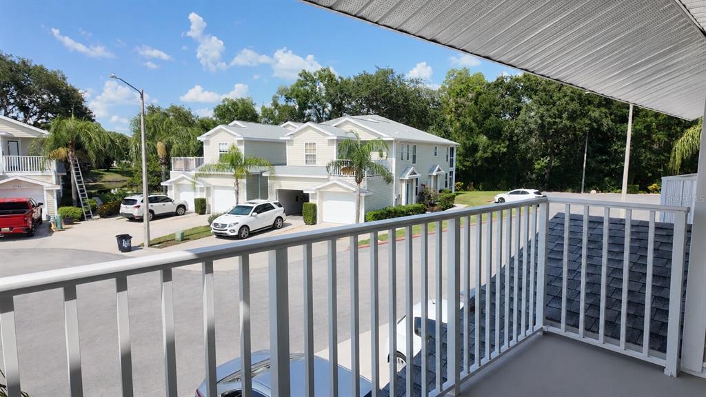 A view from a balcony overlooking a parking area, residential buildings, and trees — 1651 HAMMOCKS AVENUE, LUTZ, FL