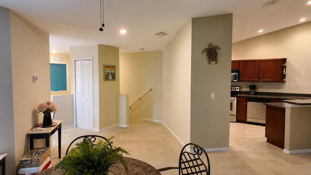 This interior view shows a carpeted living area, a staircase, and an open kitchen — 1651 HAMMOCKS AVENUE, LUTZ, FL