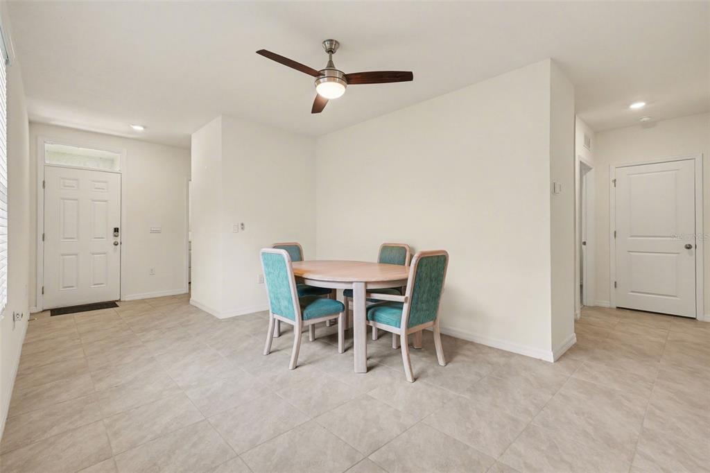 A dining area with a round wooden table, four teal chairs, and a ceiling fan — 3296 SUNCOAST PLAINS DRIVE, ODESSA, FL