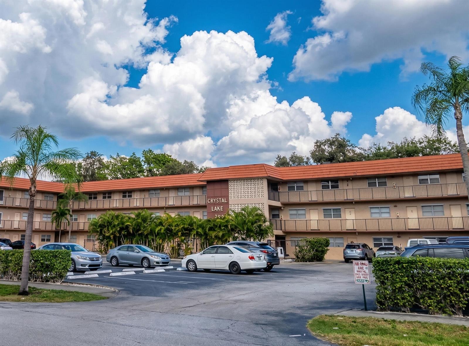 A three-story apartment building with a red tile roof and a parking lot in front — 3930 Crystal Lake Drive # 206, Deerfield Beach FL 33064, DEERFIELD BEACH, FL
