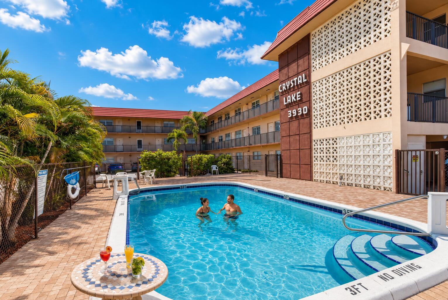 A couple swims in a pool outside a multi-story apartment building with a decorative screen — 3930 Crystal Lake Drive # 206, Deerfield Beach FL 33064, DEERFIELD BEACH, FL