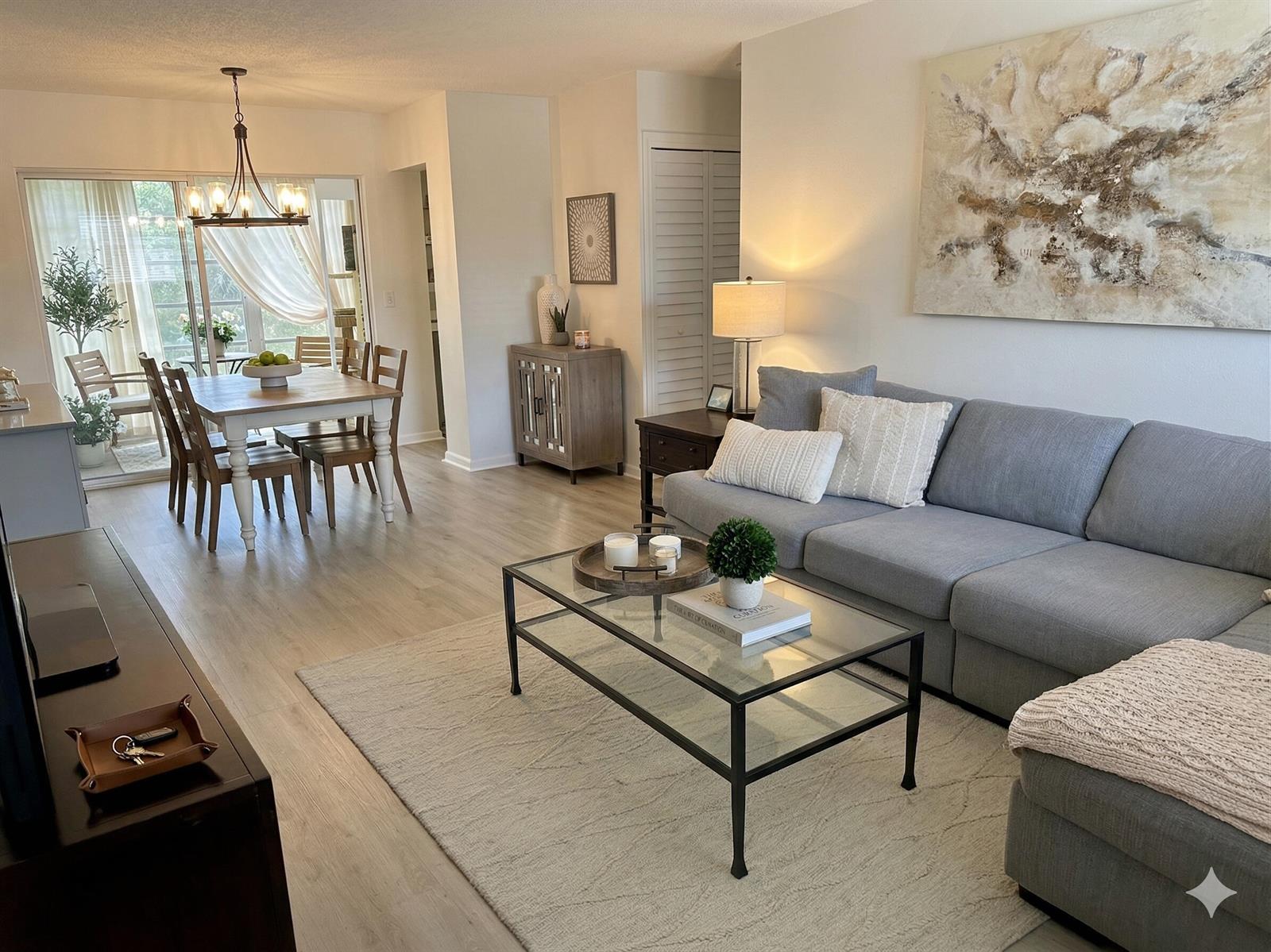 A living room with a gray sectional sofa, glass coffee table, and adjacent dining area — 3930 Crystal Lake Drive # 206, Deerfield Beach FL 33064, DEERFIELD BEACH, FL