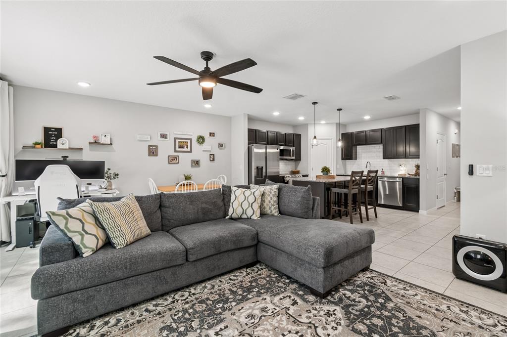 A gray sectional sofa sits in an open-concept living room with a kitchen behind it — 4733 DEER TRACK STREET, TAMPA, FL