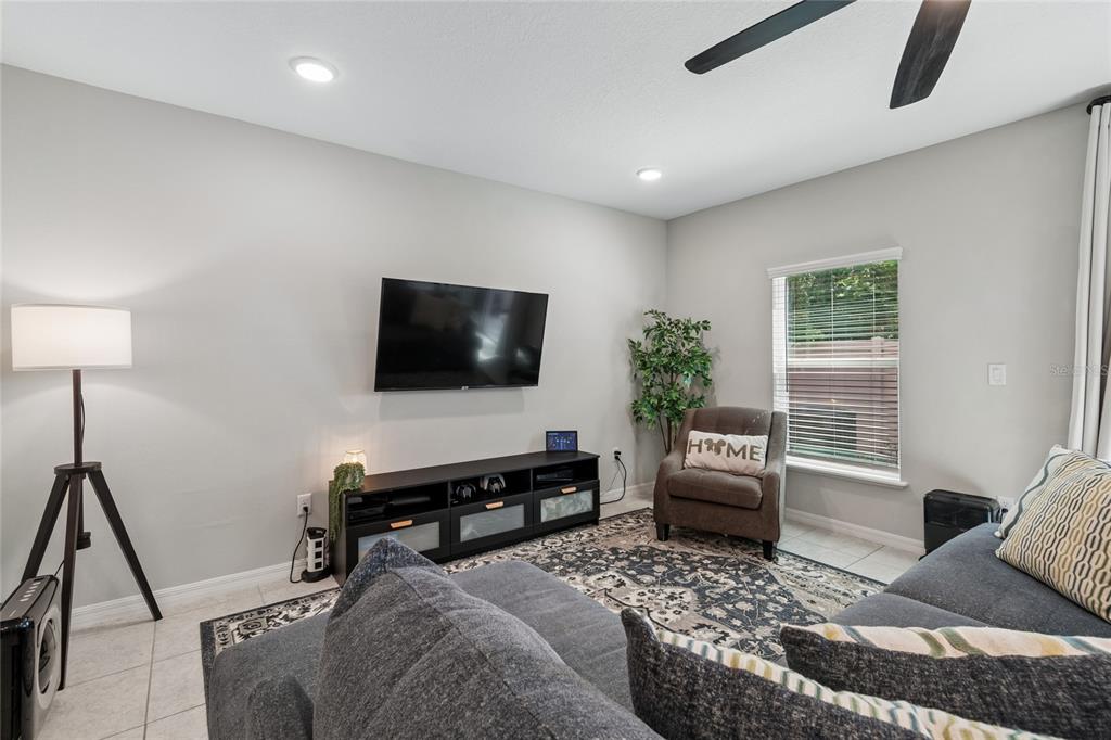 A living room features a wall-mounted television, a media console, and a gray sectional sofa — 4733 DEER TRACK STREET, TAMPA, FL