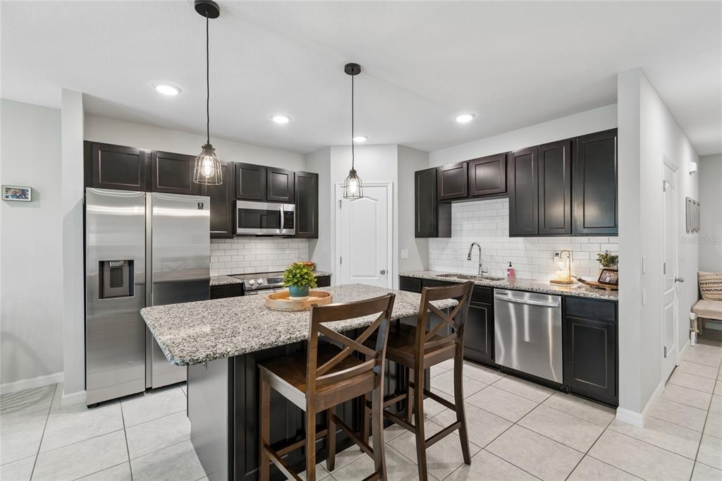 A kitchen features dark cabinetry, granite countertops, stainless steel appliances, and a central island — 4733 DEER TRACK STREET, TAMPA, FL