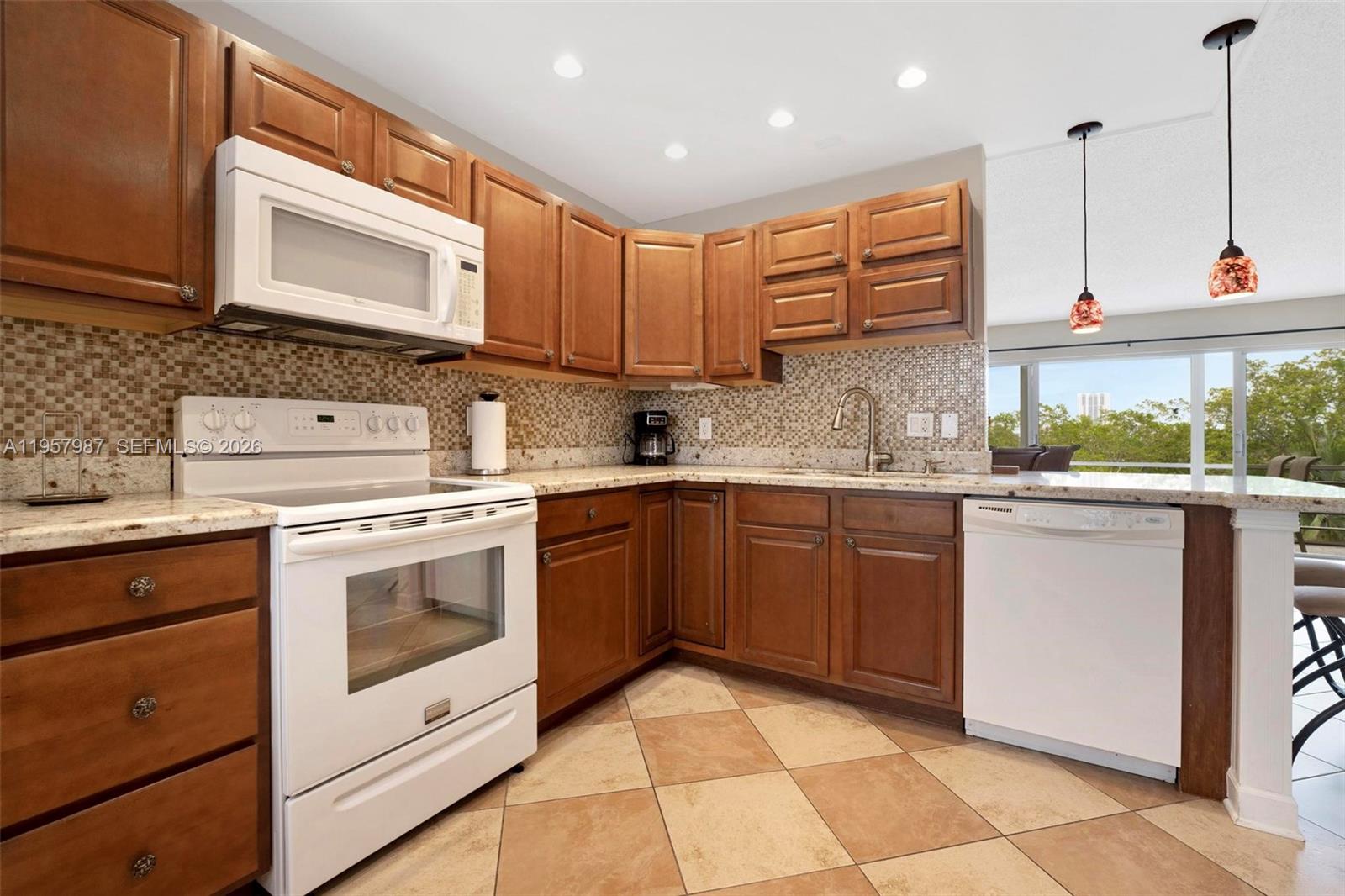 A kitchen features wood cabinets, white appliances, granite countertops, and a tiled floor — 1000 NE 14th Ave # 602, Hallandale Beach FL 33009, HALLANDALE BEACH, FL