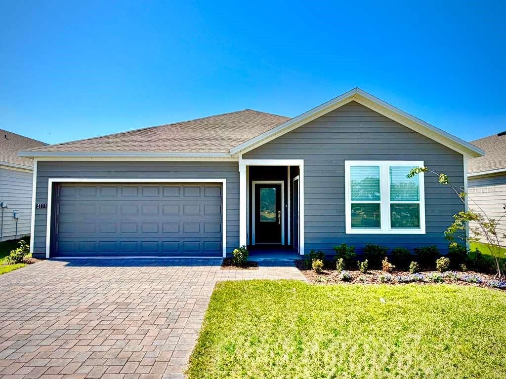 A single-story house with gray horizontal siding, a two-car garage, and a paved driveway — 5111 NATALIA DRIVE, ST CLOUD, FL